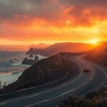 A winding highway hugging the Pacific coastline at sunset, cliffs glowing golden under a vivid orange sky, waves crashing below, and a lone car driving along the curve. The atmosphere feels adventurous and free, symbolizing the start of an epic North American road trip. Ultra‑wide landscape orientation, cinematic lighting, travel blog aesthetic.